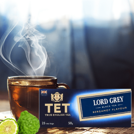 Na obrazie znajduje się filiżanka z parującą herbatą oraz opakowanie herbaty TET Lord Grey o smaku bergamotki. Opakowanie zawiera napis: \'TET TRUE ENGLISH TEA 25 tea bags 50g\' oraz \'LORD GREY BLACK TEA BERGAMOT FLAVOUR\'.