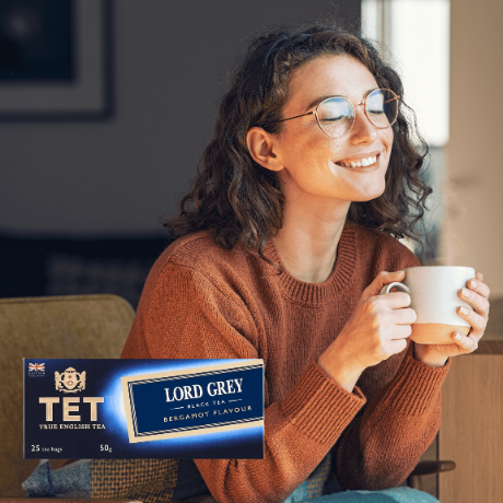 Osoba w okularach trzyma filiżankę, obok widoczne jest opakowanie herbaty z napisem \'TET TRUE ENGLISH TEA LORD GREY BLACK TEA BERGAMOT FLAVOUR 25 tea bags 50g\'.