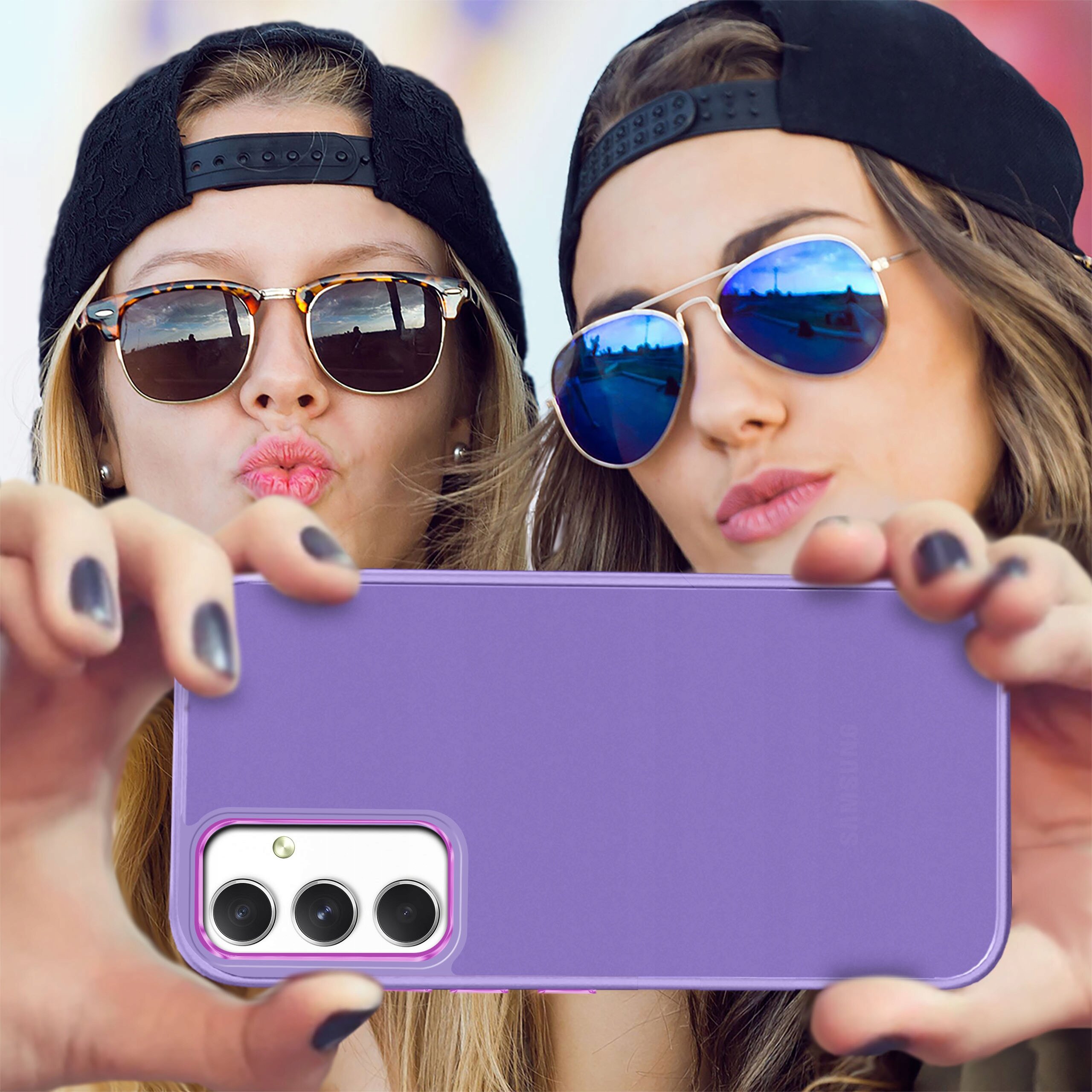 Fioletowe etui na telefon z trzema widocznymi aparatami fotograficznymi trzymane przez dwie osoby w okularach przeciwsłonecznych i czapkach z daszkiem.