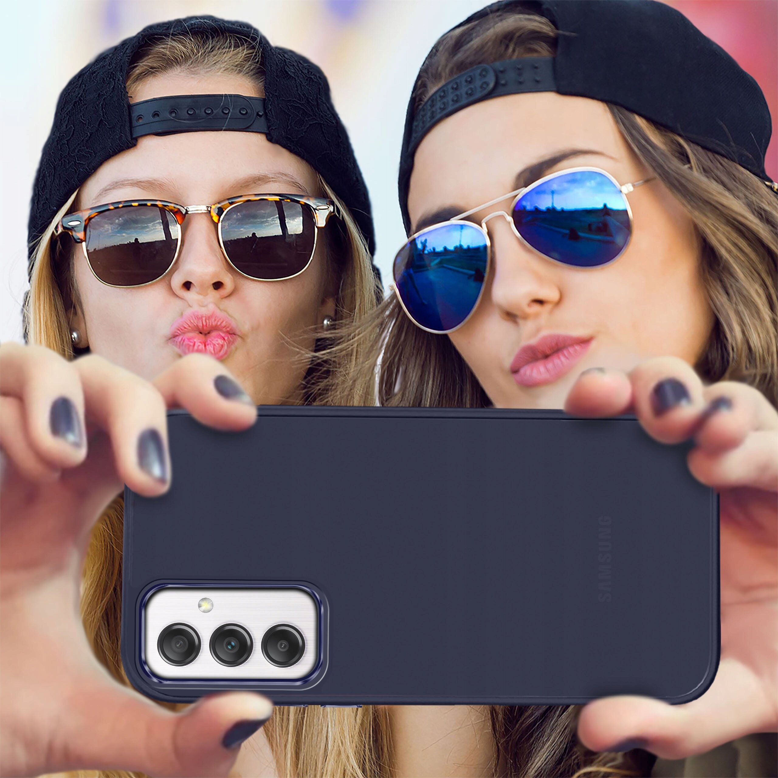 Etui do Samsung Galaxy A25 5G w kolorze matowym, trzymane przez dwie osoby w okularach przeciwsłonecznych i czapkach z daszkiem. Na etui widoczne są trzy obiektywy aparatu oraz napis \'Samsung\'.
