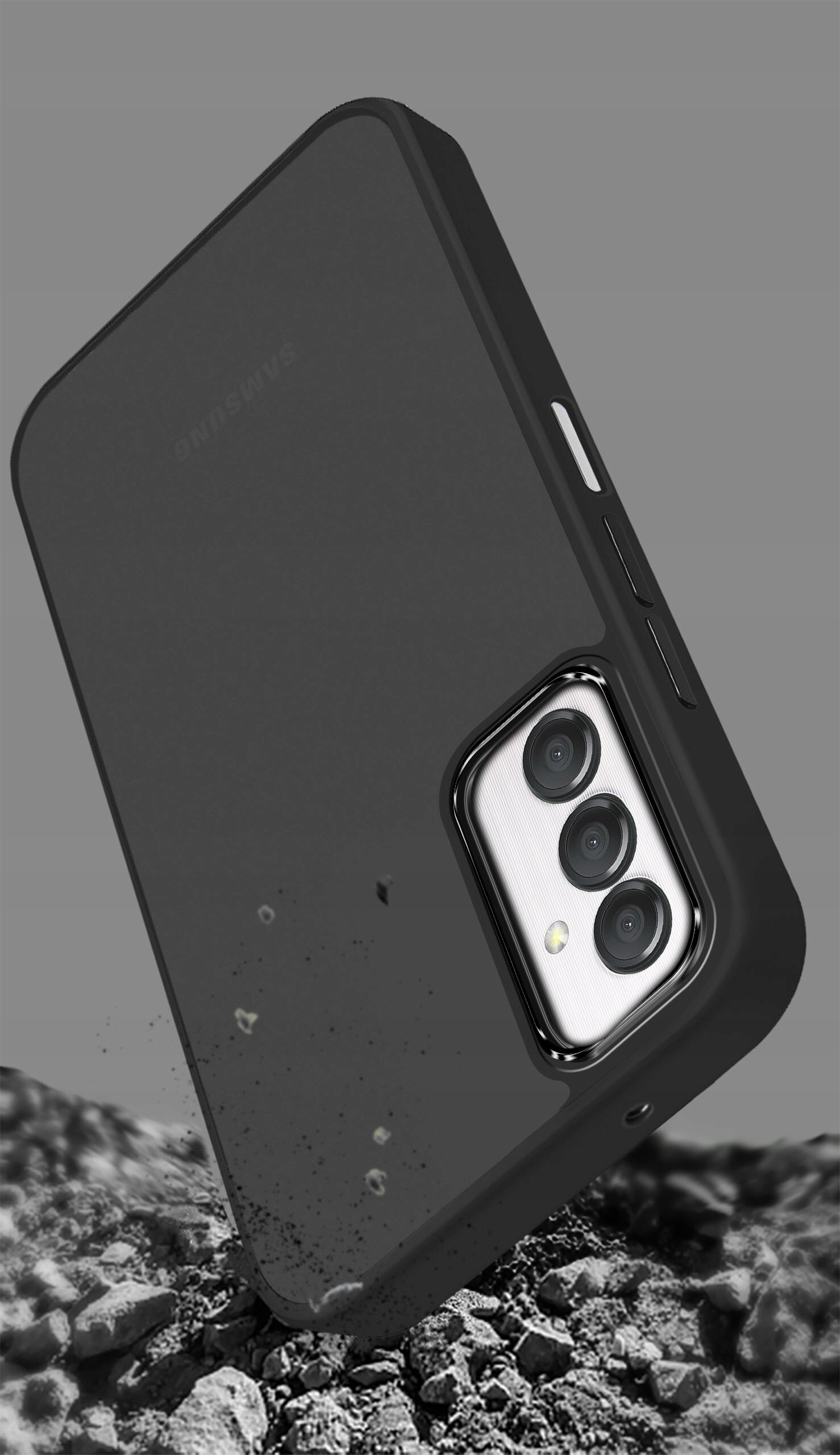 Czarne, matowe etui na telefon z trzema widocznymi obiektywami aparatu, leży na tle przypominającym kamienie. Na etui widoczny jest napis \'Samsung\'.
