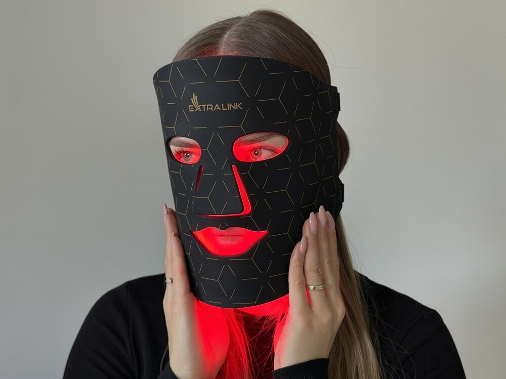 Osoba nosi czarną maskę LED z czerwonym podświetleniem, na której widoczne jest logo \'EXTRALINK\'.