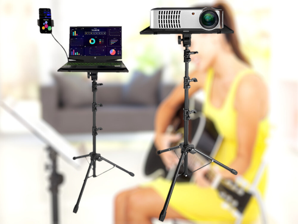 Na obrazie widoczne są dwa statywy, jeden z laptopem i telefonem, drugi z projektorem. W tle znajduje się osoba grająca na gitarze.