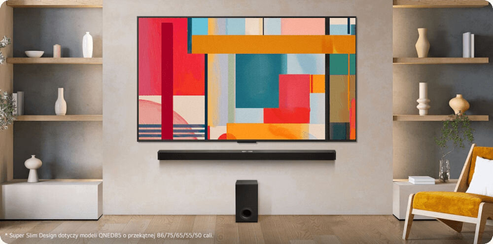 W salonie na ścianie wisi duży telewizor z kolorową abstrakcyjną grafiką na ekranie. Pod telewizorem znajduje się soundbar i subwoofer, a po bokach widoczne są półki z dekoracjami oraz fotel.