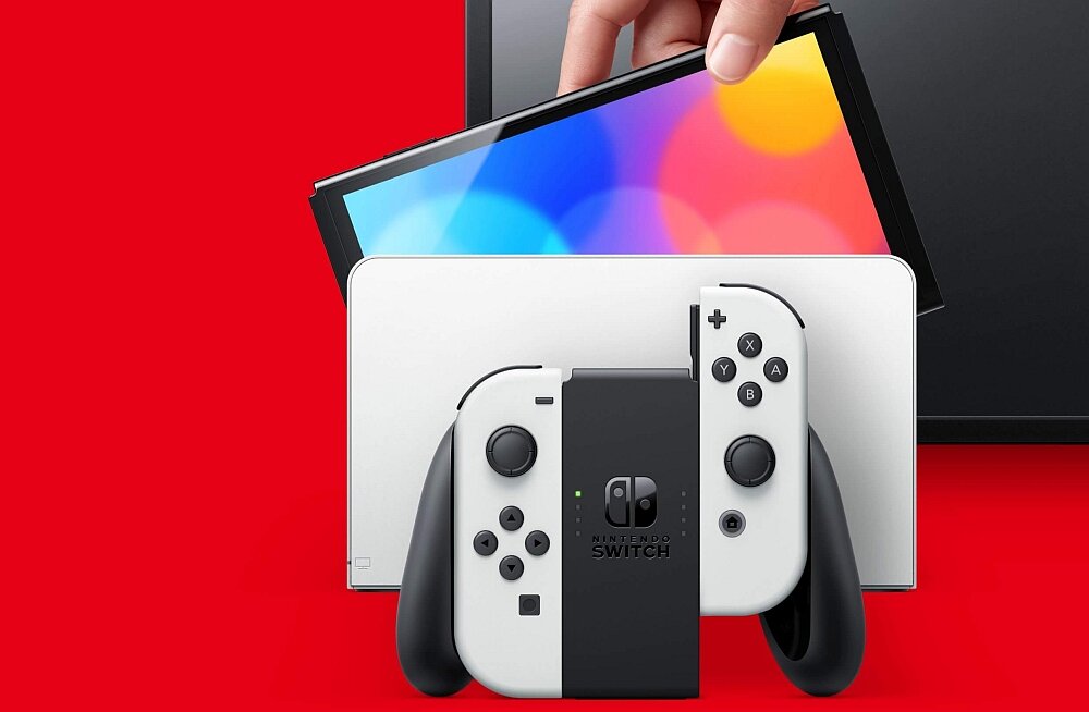 Konsola z białymi kontrolerami i kolorowym ekranem, umieszczona na czerwonym tle. Widoczne logo \'Nintendo Switch\'.