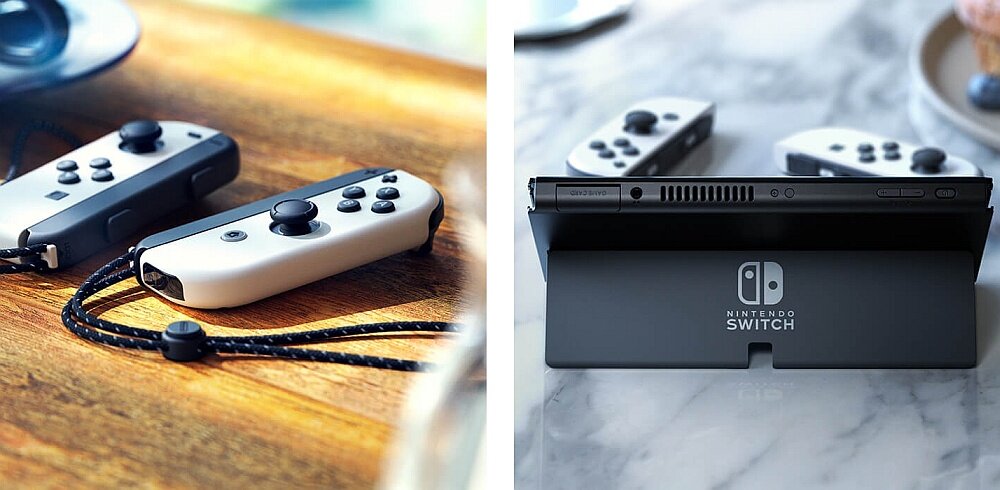 Na drewnianym stole leżą dwa kontrolery do konsoli w kolorze szarym z czarnymi przyciskami. Obok na marmurowym blacie znajduje się konsola z logo \'NINTENDO SWITCH\' na podstawce.