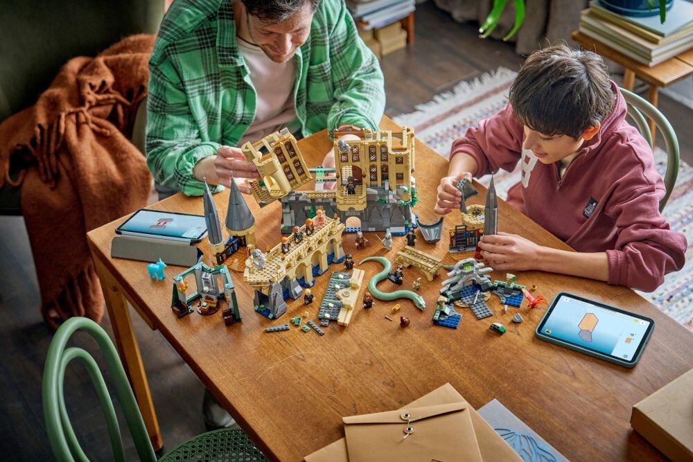 На столі лежить набір LEGO із зображенням замку з вежами та персонажами. Поруч — планшет з інструкціями зі складання.