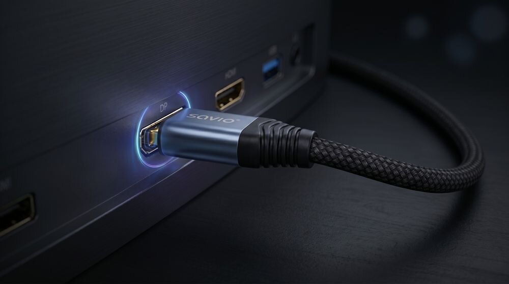 Kabel DisplayPort z napisem \'savio\' podłączony do portu oznaczonego jako \'DP\' w urządzeniu elektronicznym. Kabel ma plecioną osłonę i metalową końcówkę.