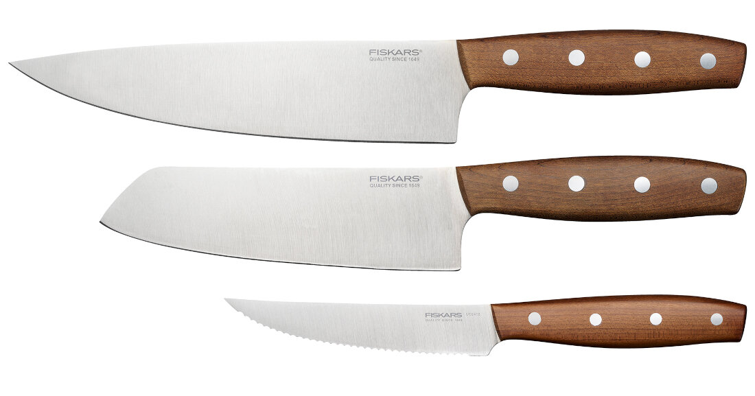 Na obrazie widoczne są trzy noże z drewnianymi rękojeściami i stalowymi ostrzami. Na ostrzach widnieje napis \'FISKARS QUALITY SINCE 1649\'.