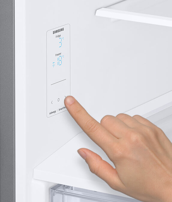 Na obrazie widoczny jest panel sterowania lodówki z logo \'SAMSUNG\', na którym wyświetlane są temperatury: \'Fridge 3°C\' i \'Freezer -18°C\'. Dłoń dotyka panelu, a poniżej widoczne są napisy \'Allergy\' i \'SmartThings\'.