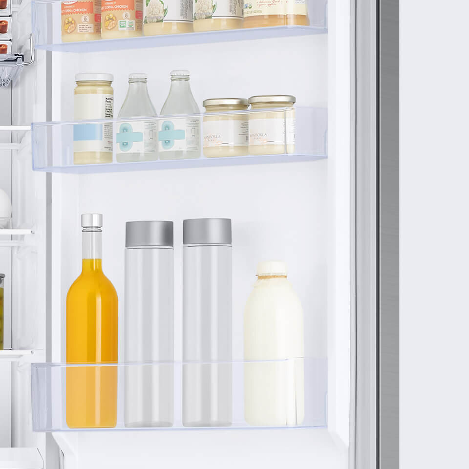 Wnętrze drzwi lodówki z trzema półkami, na których znajdują się różne produkty spożywcze, w tym butelki i słoiki. Półki są przezroczyste, a produkty mają różne kolory i kształty.