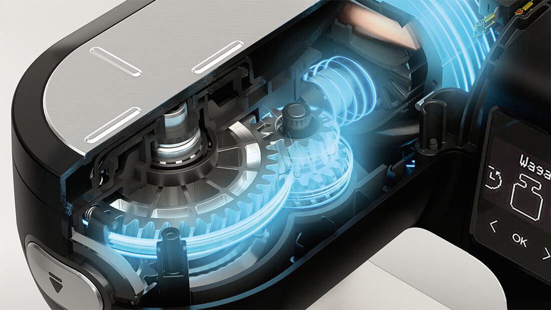 Obraz przedstawia wnętrze robota kuchennego z widocznymi mechanizmami i podświetleniem na niebiesko. Na wyświetlaczu widoczny jest symbol wagi oraz przyciski z napisem \'OK\'.