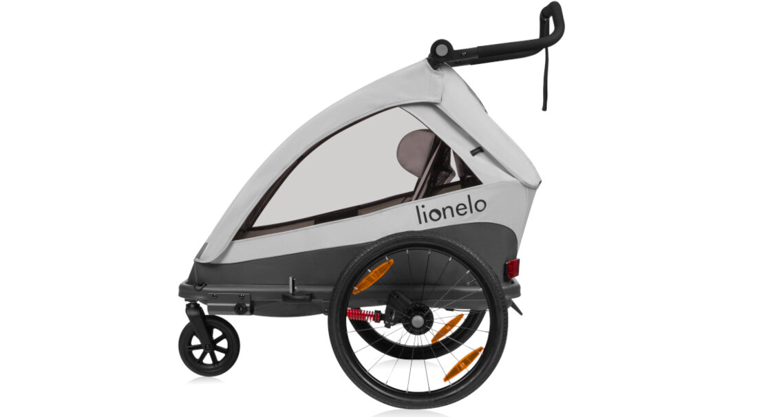 Szara przyczepka rowerowa z logo \'lionelo\', wyposażona w dwa duże koła z pomarańczowymi odblaskami i jedno mniejsze koło z przodu. Przyczepka ma przezroczyste okienko i czarny uchwyt.