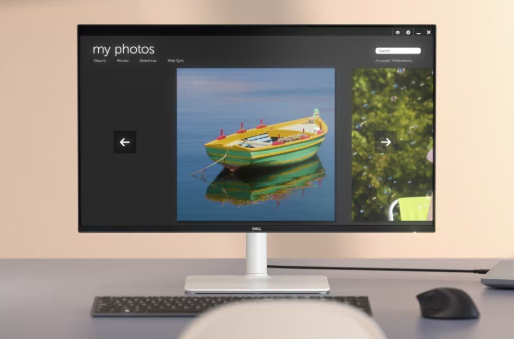 Monitor wyświetla zdjęcie żółtej łodzi na wodzie z aplikacją \'my photos\'. Na obudowie monitora widoczne jest logo \'DELL\'.