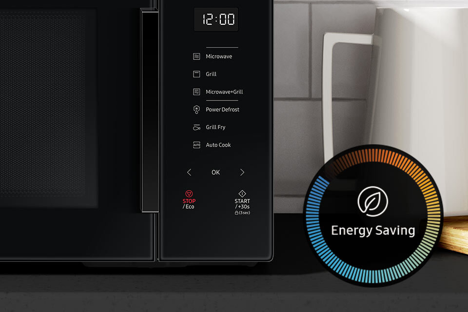 Panel sterowania kuchenki mikrofalowej z wyświetlaczem pokazującym godzinę 12:00 oraz przyciskami do wyboru funkcji takich jak Microwave, Grill, Microwave+Grill, Power Defrost, Grill Fry, Auto Cook. Obok znajduje się okrągły wskaźnik z napisem \'Energy Saving\'.