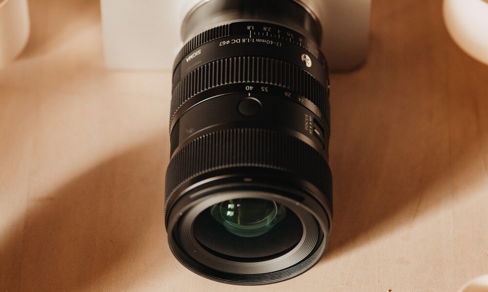 Czarny obiektyw fotograficzny z widocznymi oznaczeniami \'SIGMA\' i \'17-50mm 1:2.8 EX DC OS\'.