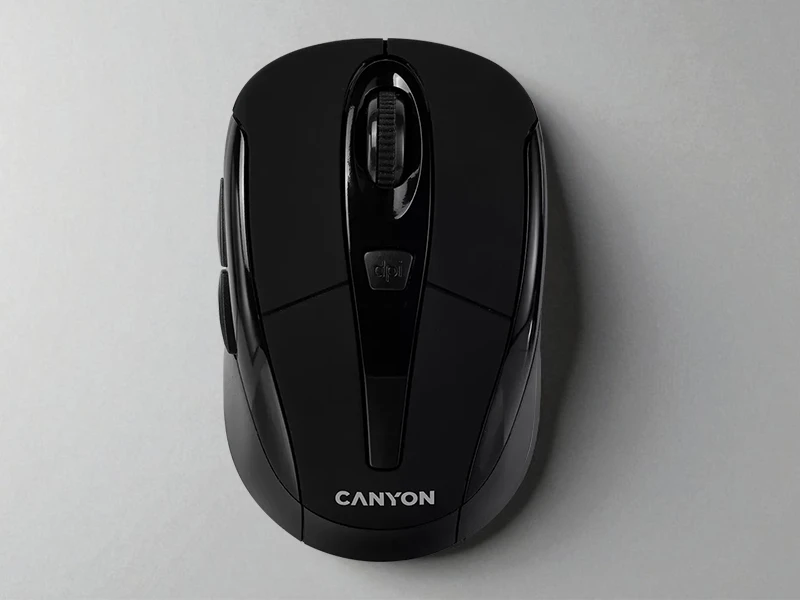 Czarna mysz bezprzewodowa z logo \'CANYON\' na dolnej części obudowy. Na górze znajduje się przycisk z napisem \'dpi\' oraz rolka przewijania.