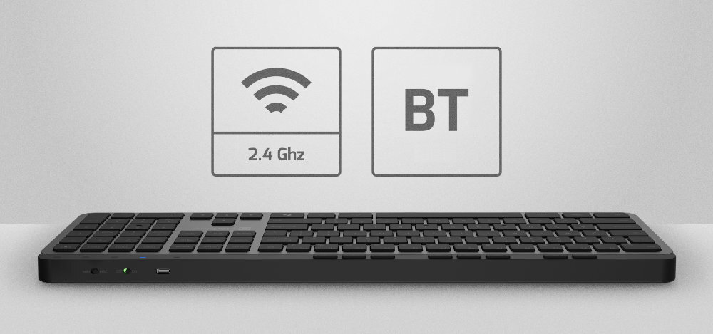Na obrazie widoczna jest czarna klawiatura z niskim profilem klawiszy. Nad nią znajdują się ikony z symbolami łączności: \'2.4 Ghz\' i \'BT\'.