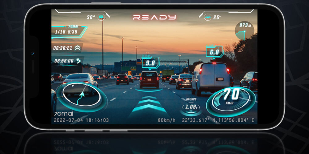 Na ekranie urządzenia widać widok z wideorejestratora przedstawiający ruch uliczny z nałożonymi danymi, takimi jak prędkość 70 km/h, współrzędne GPS oraz czas 2022-07-04 18:16:03. Widoczne są również oznaczenia 70mai i napis \'READY\'.