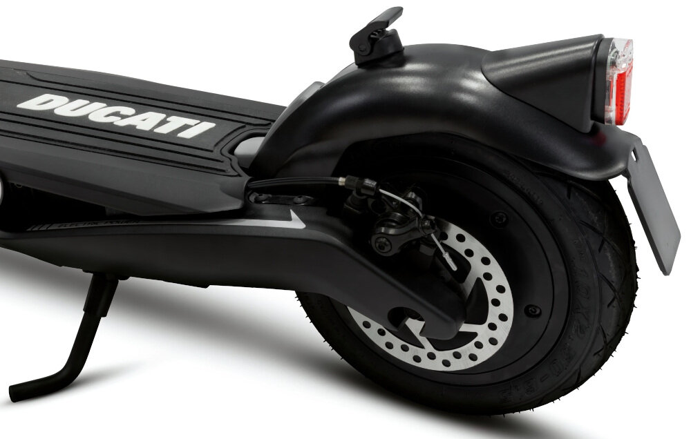 Czarna hulajnoga elektryczna z widocznym tylnym kołem, hamulcem tarczowym i napisem \'DUCATI\' na podeście. Tylne światło jest włączone, a obok znajduje się podpórka.