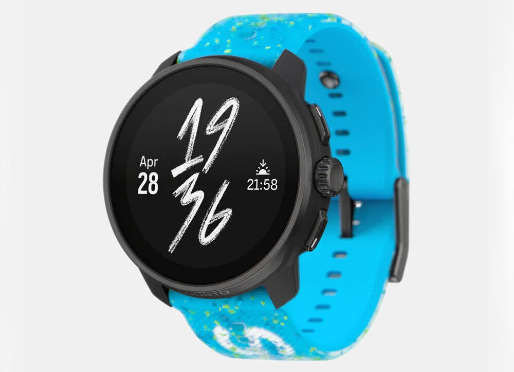 Smartwatch z czarną kopertą i niebieskim paskiem z kolorowymi wzorami. Na wyświetlaczu widoczna jest data \'Apr 28\' oraz godzina \'19:36\'.