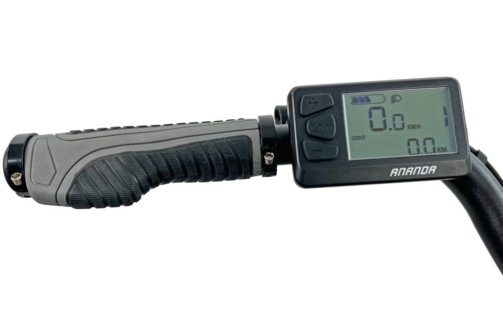 Obraz przedstawia kierownicę roweru z wyświetlaczem elektronicznym. Na ekranie widoczny jest napis \'ANANDA\' oraz wartości \'0.0 KM/H\' i \'0.0 KM\'.