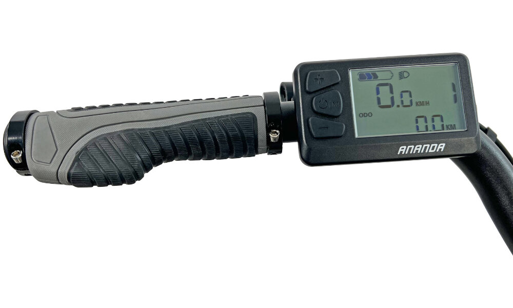 Obraz przedstawia uchwyt roweru z wyświetlaczem elektronicznym. Na ekranie widoczny jest tekst: \'ODO 0.0 KM/H 0.0 KM\', a poniżej logo \'ANANDA\'.