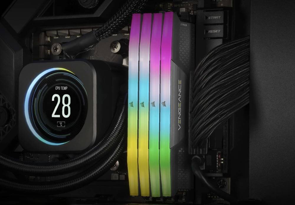 Obraz przedstawia wnętrze komputera z widocznymi modułami pamięci RAM z podświetleniem RGB w kolorach tęczy. Na wyświetlaczu obok widoczna jest temperatura CPU: 28 stopni.