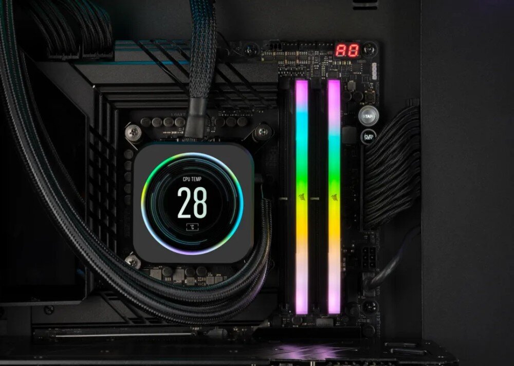 Wnętrze komputera z widocznymi dwoma modułami pamięci RAM z podświetleniem RGB oraz chłodzeniem procesora z wyświetlaczem pokazującym \'CPU TEMP 28\'.