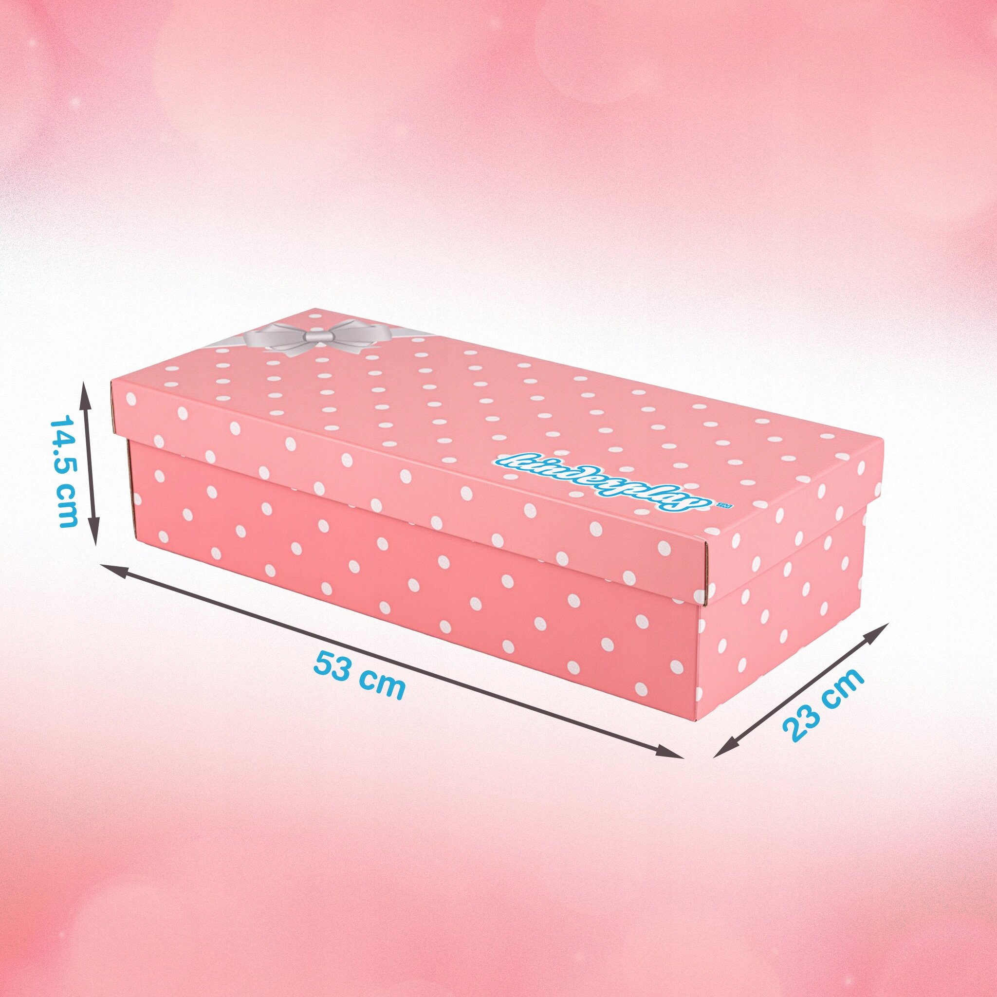 Różowe pudełko w białe kropki z napisem \'littledollls\' i wymiarami: 53 cm długości, 23 cm szerokości, 14,5 cm wysokości.