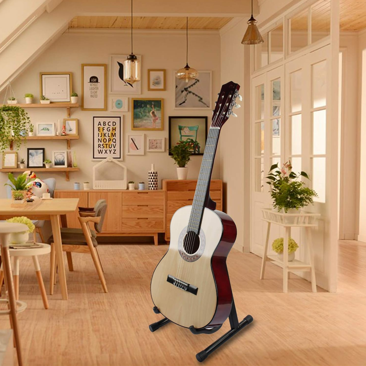 W jasnym, przytulnym wnętrzu z drewnianymi meblami i roślinami stoi gitara na czarnym, składanym statywie podłogowym. Na ścianie widoczne są różne obrazy i grafiki, w tym plakat z literami alfabetu.