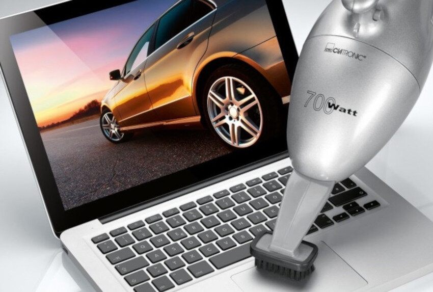 Na obrazie widoczny jest srebrny odkurzacz ręczny z napisem \'70 Watt\' i logo \'CLATRONIC\', skierowany na klawiaturę laptopa. Na ekranie laptopa wyświetlony jest obraz samochodu na tle zachodzącego słońca.
