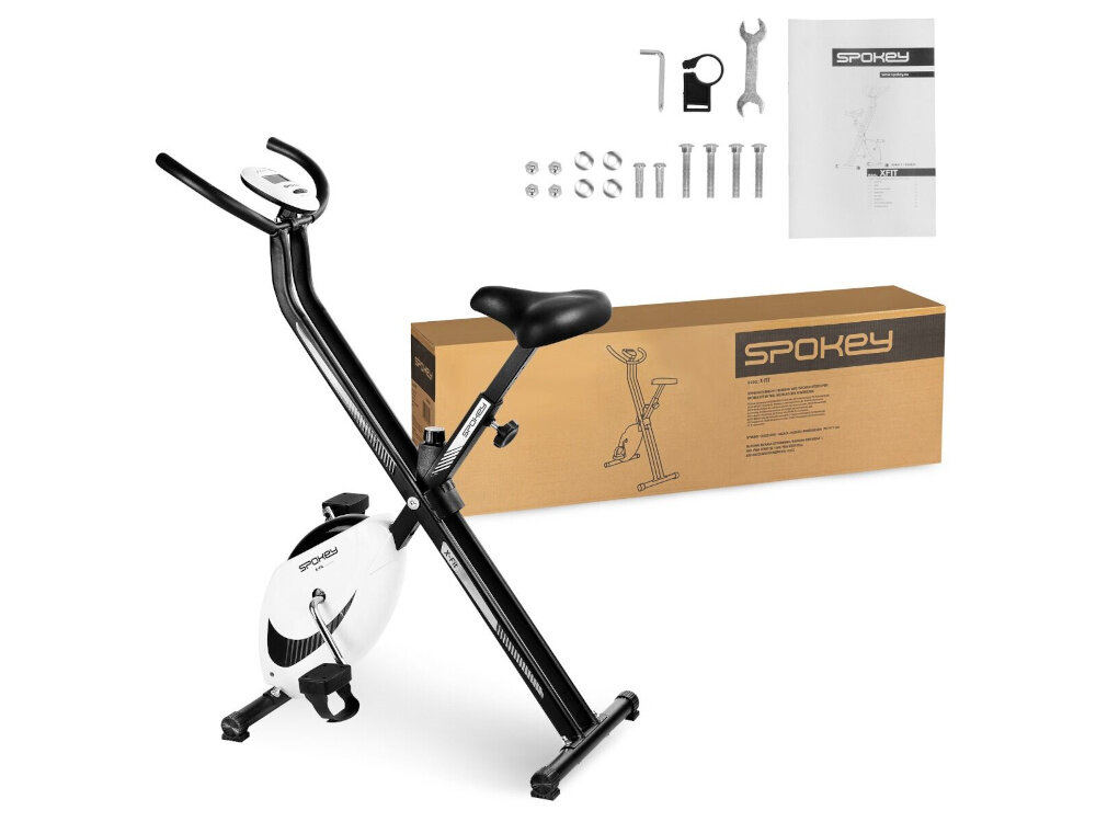 Na obrazie znajduje się czarny rower mechaniczny z białym kołem, obok którego leży karton z napisem \'SPOKEY\'. W tle widoczne są narzędzia montażowe oraz instrukcja z logo \'SPOKEY\'.