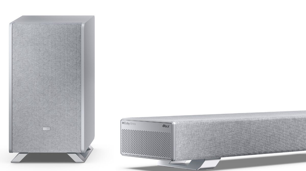 Na obrazie widoczny jest srebrny soundbar oraz bezprzewodowy subwoofer. Na soundbarze znajdują się napisy: \'Dolby Atmos\' i \'dtsX\'.