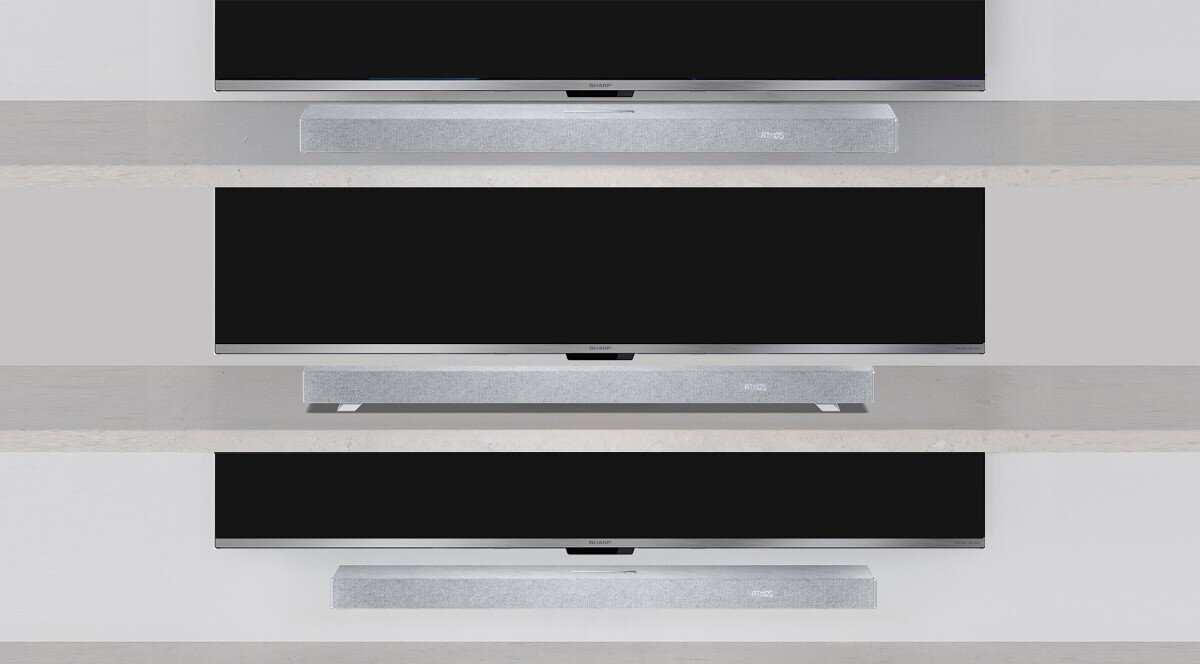 Na obrazie widoczne są trzy srebrne soundbary umieszczone pod telewizorami na różnych wysokościach. Każdy soundbar ma prosty, nowoczesny design i znajduje się na tle jasnej ściany.