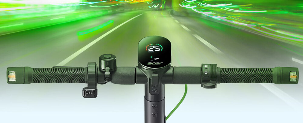 Kierownica hulajnogi elektrycznej z wyświetlaczem pokazującym prędkość 25 km/h i logo \'acer\'. W tle rozmyta droga z zielonymi i żółtymi światłami.