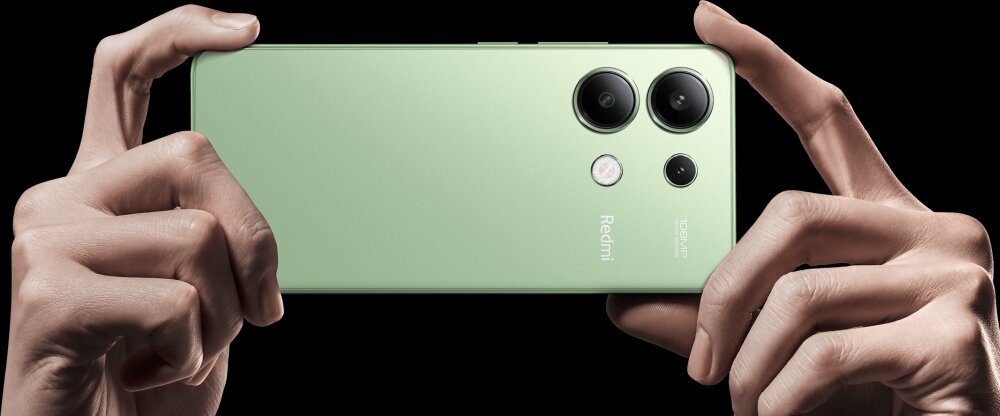 Zielony smartfon trzymany w dłoniach, z widocznymi trzema obiektywami aparatu i napisem \'Redmi\' oraz \'108MP\'.