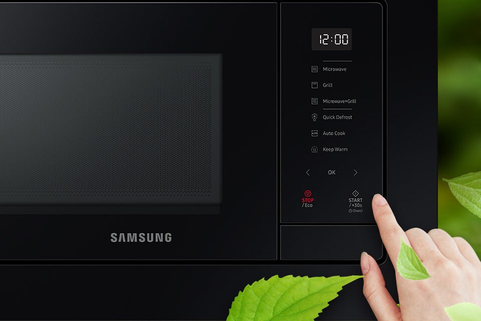 Czarna kuchenka mikrofalowa z panelem dotykowym, na którym widoczne są opcje: Microwave, Grill, Microwave+Grill, Quick Defrost, Auto Cook, Keep Warm. Na wyświetlaczu widnieje godzina 12:00, a poniżej przyciski STOP/Eco i START/+30s, obok logo Samsung.