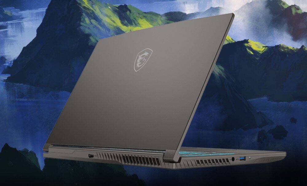 Laptop z zamkniętą pokrywą, na której widoczne jest logo producenta. W tle znajduje się malowniczy krajobraz z górami i wodą.