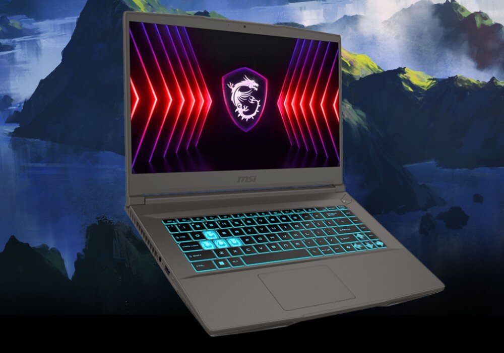 Laptop z podświetlaną klawiaturą i ekranem wyświetlającym logo smoka na tle kolorowych linii. W tle widoczny jest krajobraz z górami i wodą.
