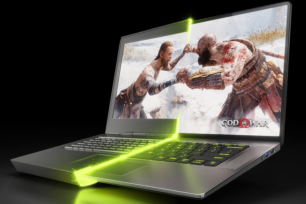 Laptop z wyświetlaczem pokazującym scenę z gry \'God of War\', z zielonym efektem świetlnym biegnącym przez klawiaturę i ekran. Na ekranie widoczni są dwaj wojownicy w dynamicznej scenie walki.