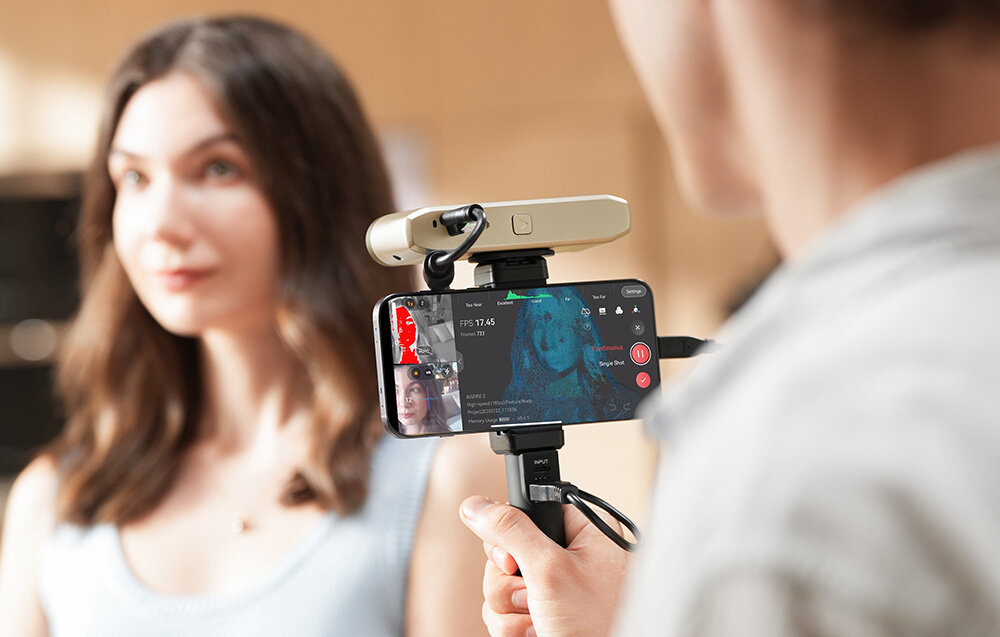 Ujęcie od strony operatora na ekran smartfona podłączonego do skanera Revopoint Inspire 2 z widocznym procesem tworzenia trójwymiarowego modelu twarzy