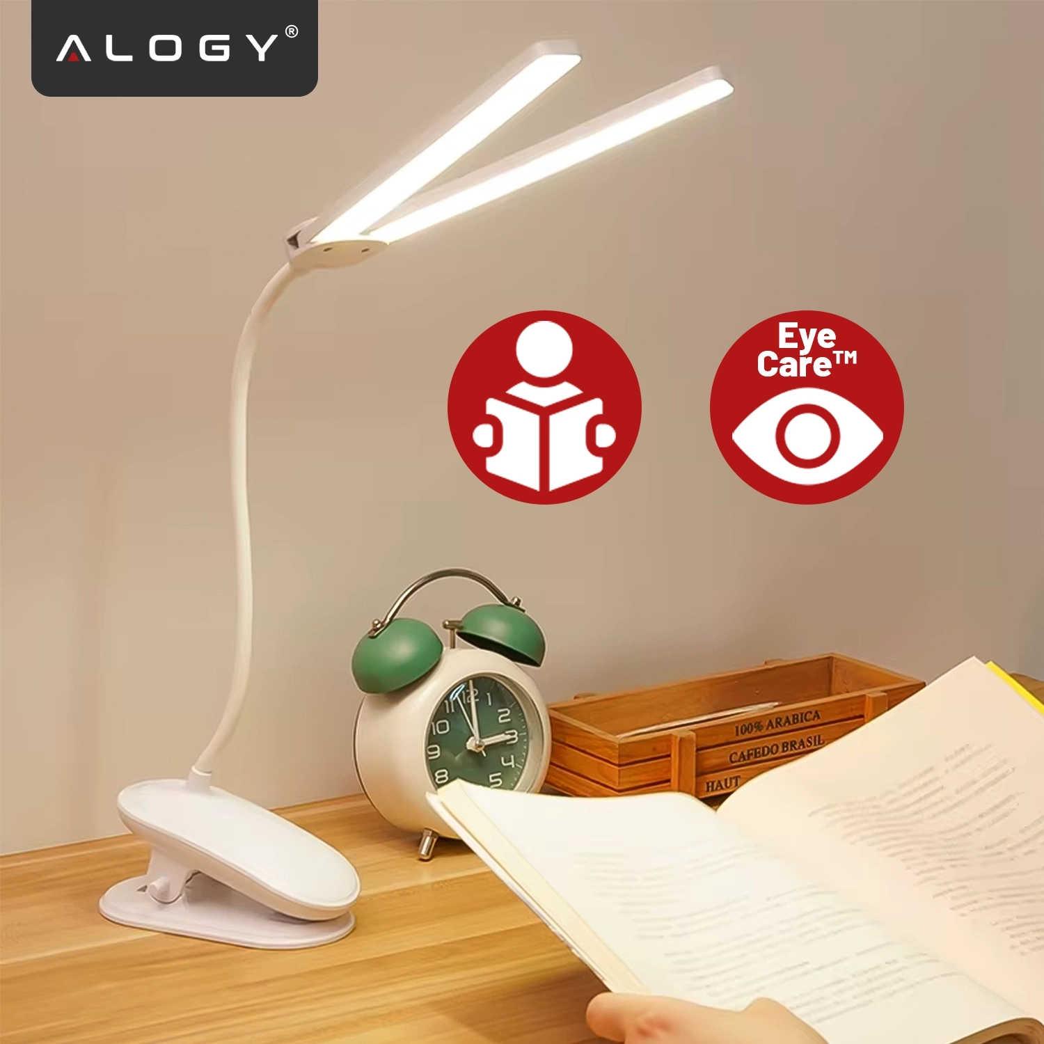 Na drewnianym biurku stoi biała lampka biurkowa z klipsem, obok której znajduje się zielony budzik. Na ścianie widoczne są dwa czerwone symbole: postać z książką i oko z napisem \'Eye Care™\'.