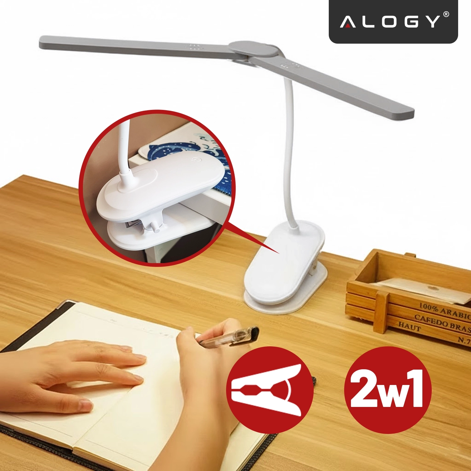 Na drewnianym biurku znajduje się biała lampka biurkowa z elastycznym ramieniem i klipsem, obok której ktoś pisze w notesie. W prawym górnym rogu widoczne jest logo \'ALOGY\', a na dole czerwone kółko z napisem \'2w1\'.
