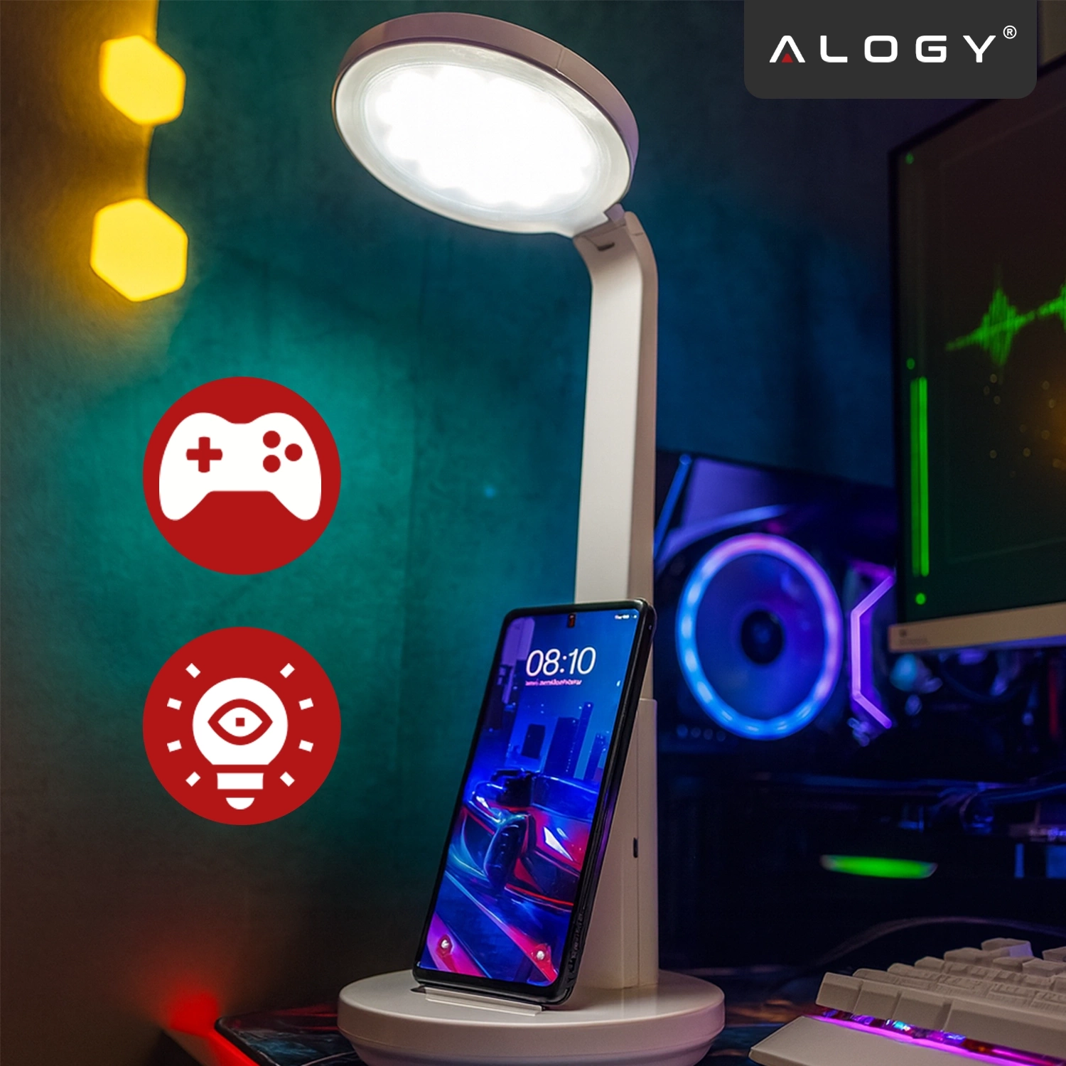 Lampka biurkowa LED z okrągłym kloszem, pod którą znajduje się stojak na smartfon. W tle widoczne są elementy komputerowe oraz logo \'ALOGY\'.