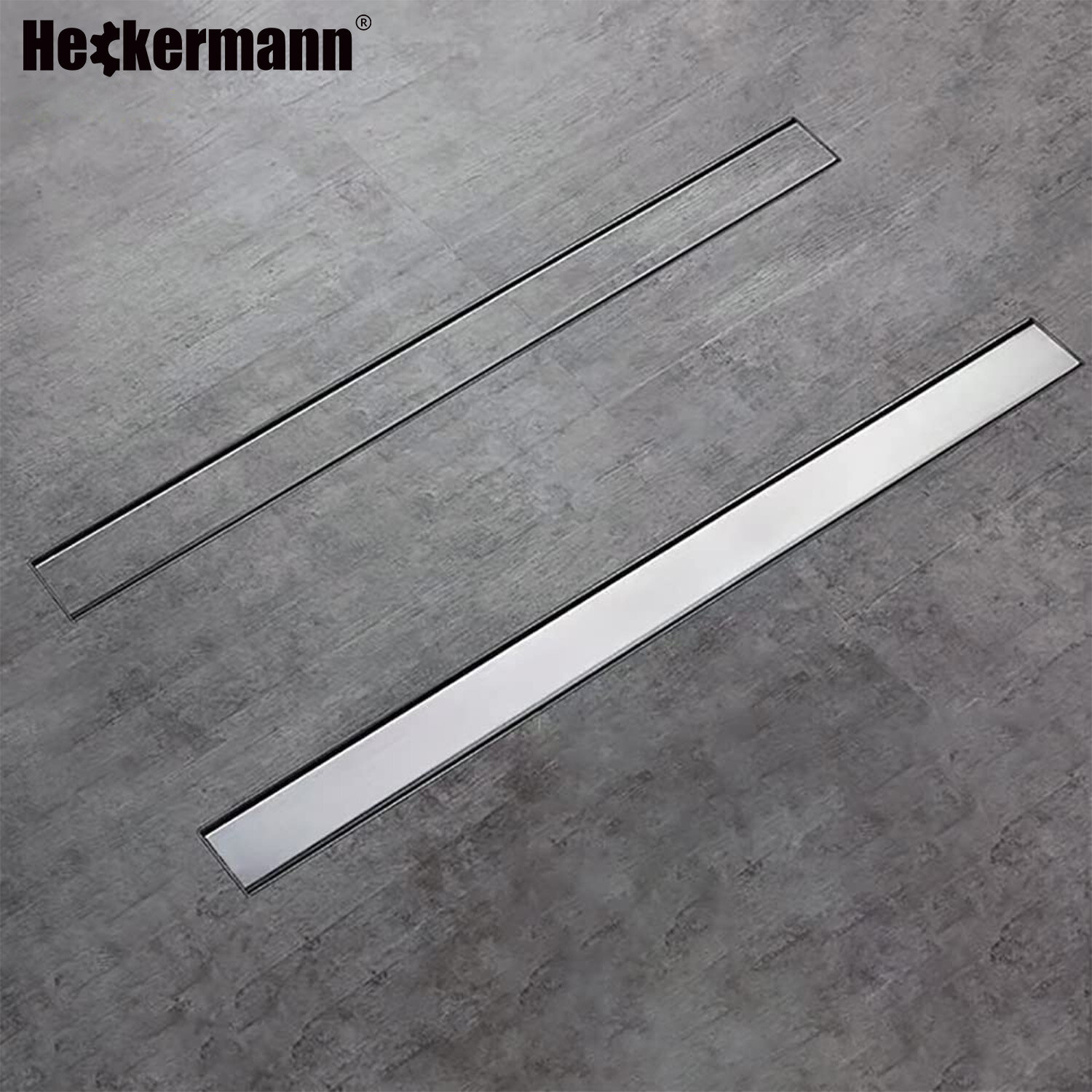 Na zdjęciu widoczny jest odpływ liniowy prysznicowy podłogowy Heckermann 70cm w kolorze srebrnym, umieszczony na szarej powierzchni. W lewym górnym rogu znajduje się logo \'Heckermann\'.