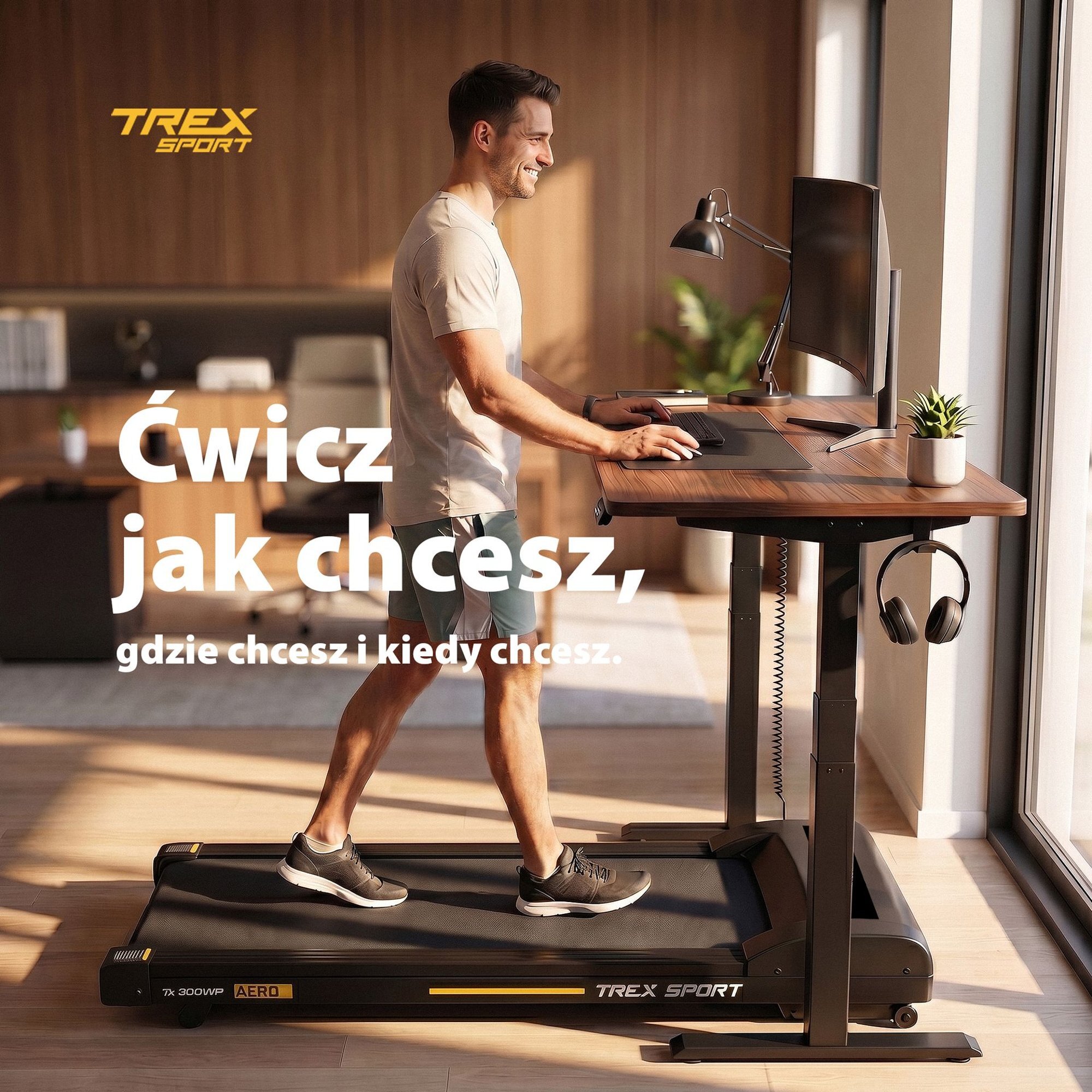 Osoba ćwiczy na bieżni elektrycznej umieszczonej pod biurkiem z komputerem. Na obrazie widoczny jest tekst: \'Ćwicz jak chcesz, gdzie chcesz i kiedy chcesz.\'
