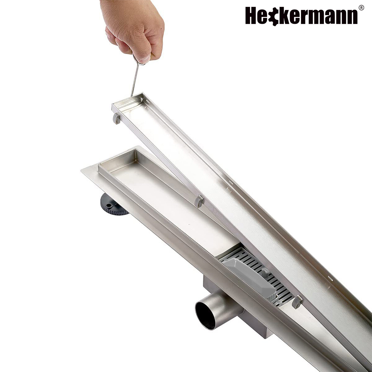 Odpływ liniowy prysznicowy podłogowy Heckermann 70cm Srebrny z widocznym logo \'Heckermann\' w prawym górnym rogu oraz ręką trzymającą narzędzie do podnoszenia pokrywy.