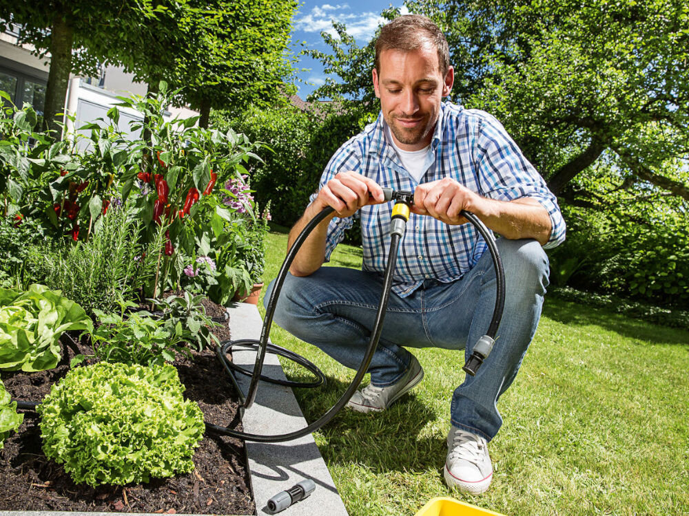 Zestaw do nawadniania KARCHER Rain System 2.645-238.0, Konstrukcja, narzędzia, bezproblemowe, samodzielnie, w tle ogród, mężczyzna instaluje podłączenie zestawu do nawadniania