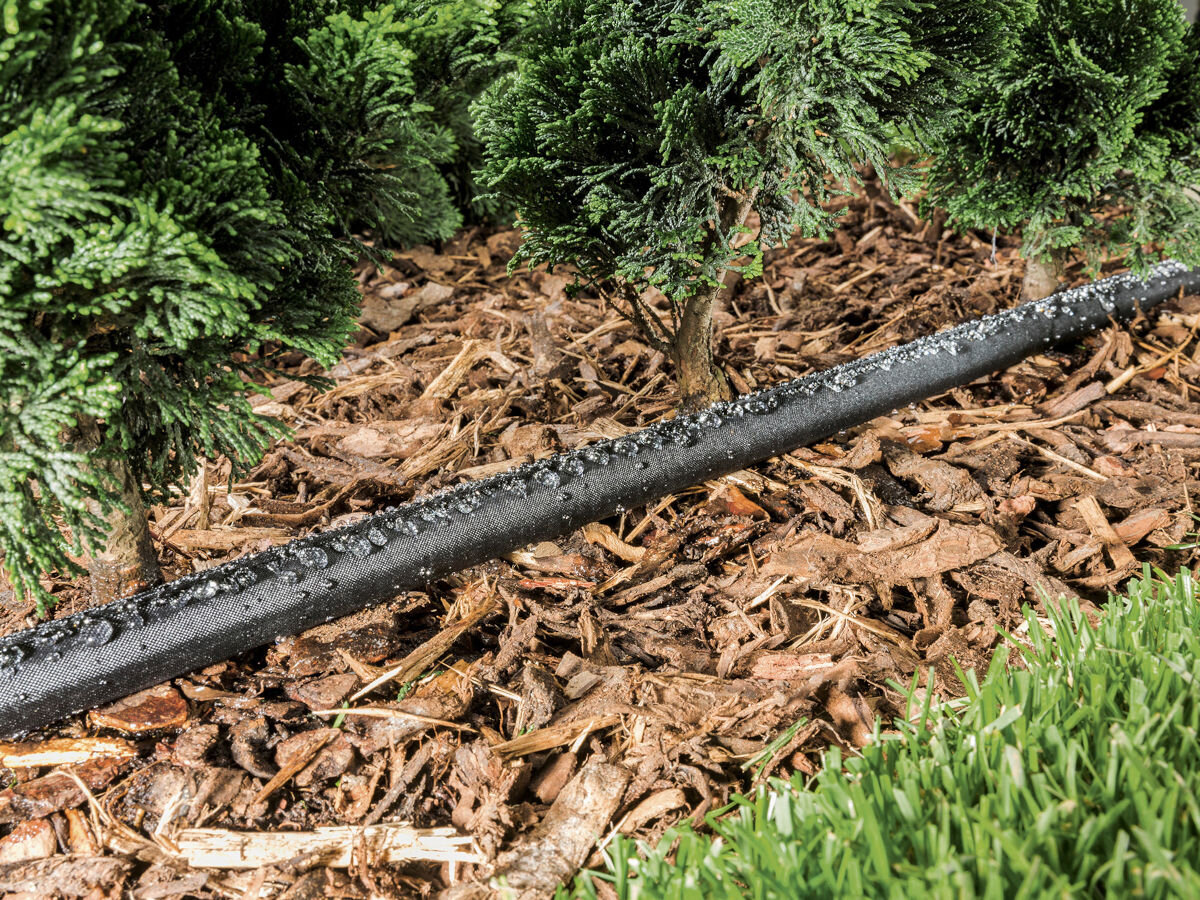 Zestaw do nawadniania KARCHER Rain System 2.645-238.0, odporne, warunki, pogoda, atmosferyczne, wąż z zestawu leży na wyściółce kory podlewając podłoże thuji